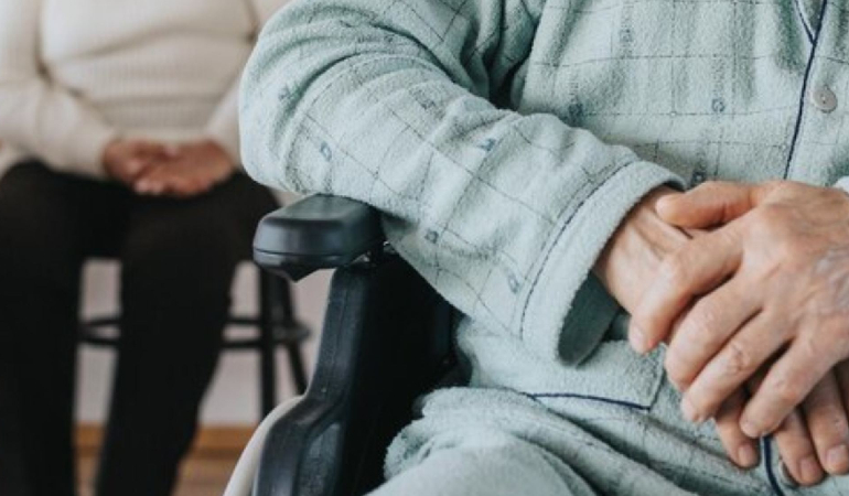 A Palliative Care specialist in India speaking gently with a senior resident, highlighting empathetic communication.