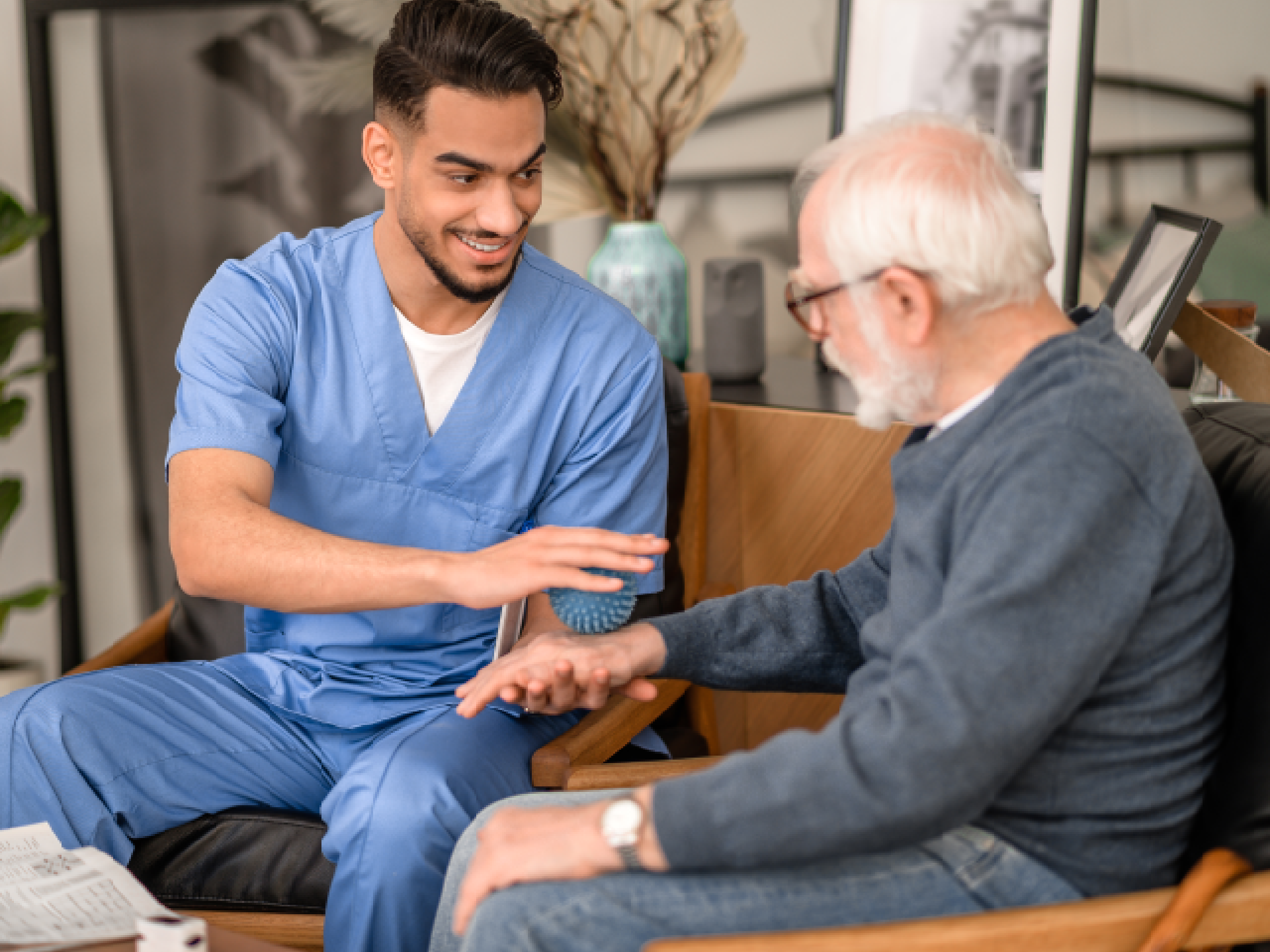 A professional caregiver is assisting a senior man with a gentle smile in a comfortable, modern assisted living apartment.