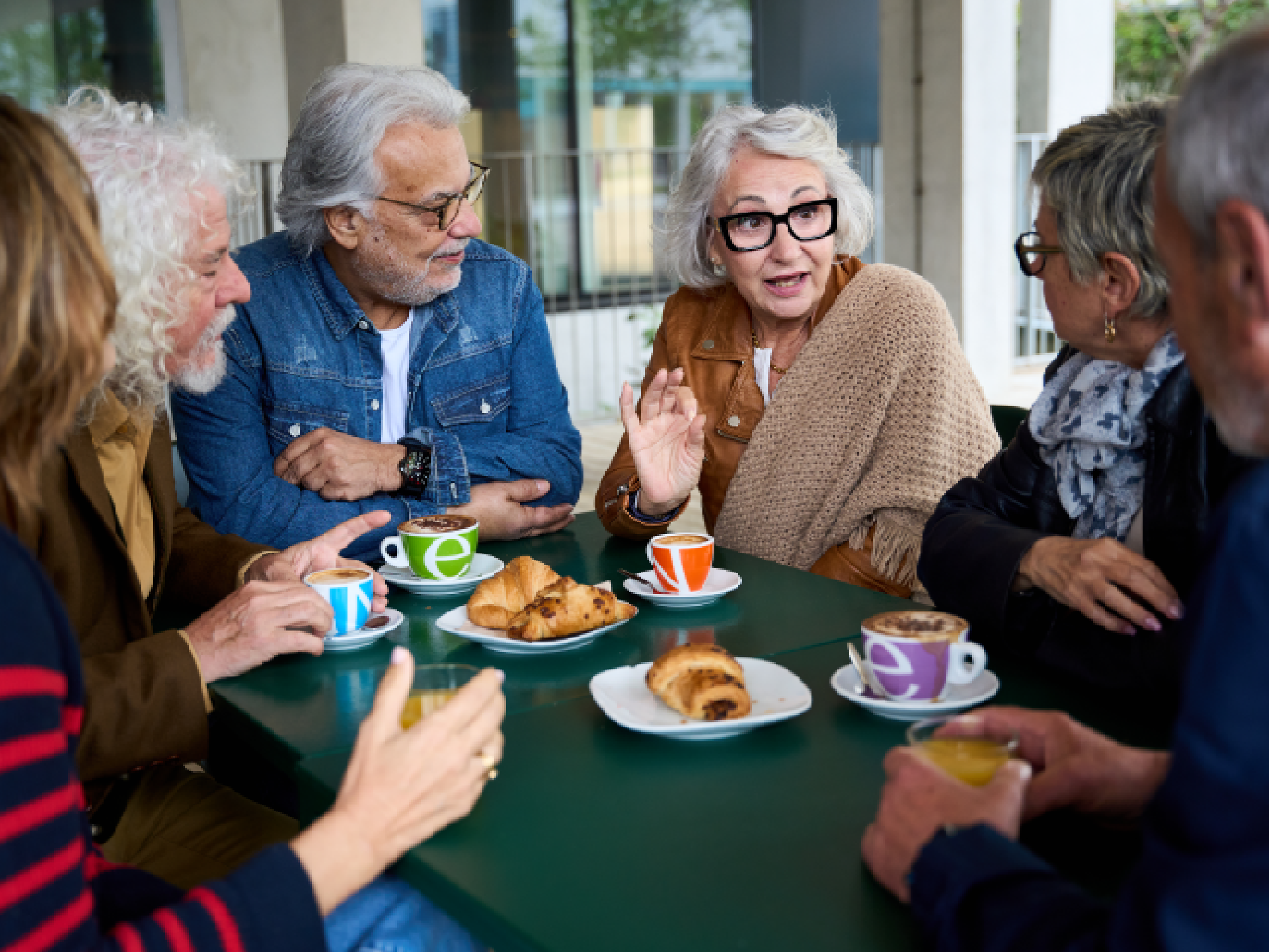 A group of senior women are laughing and talking during a card game in a comfortable and elegant common room