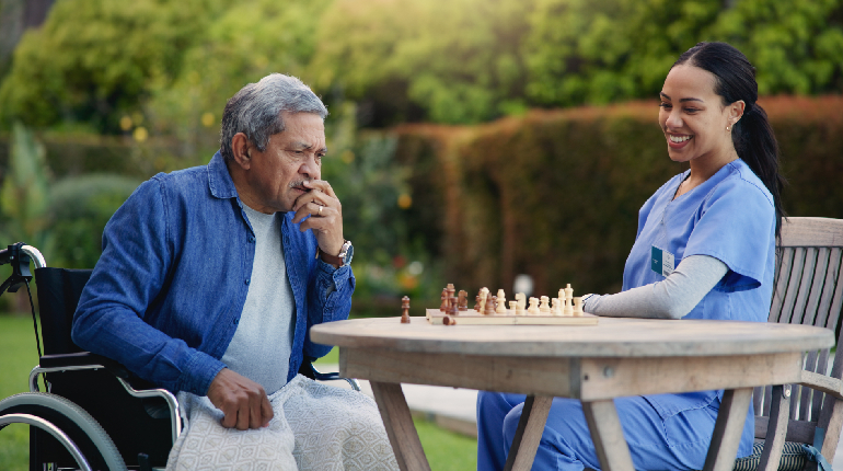 A senior resident engaged in a tactile, memory-stimulating activity with a caregiver in an Alzheimers Care center