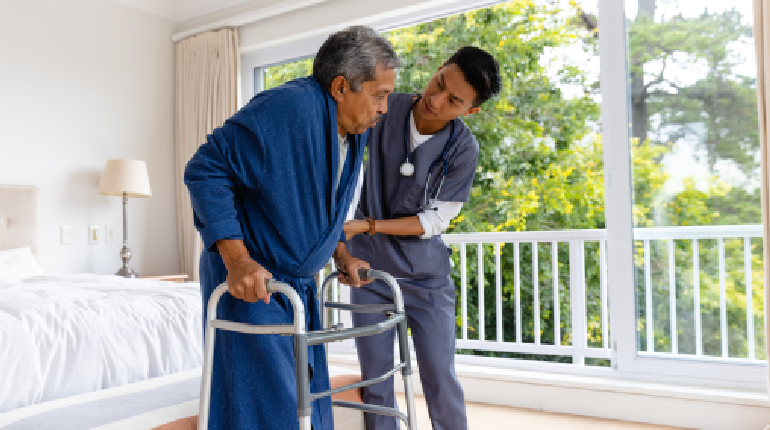 A senior stroke survivor practicing walking with specialized equipment under the guidance of a physiotherapist in a Senior care home for stroke recovery in India.