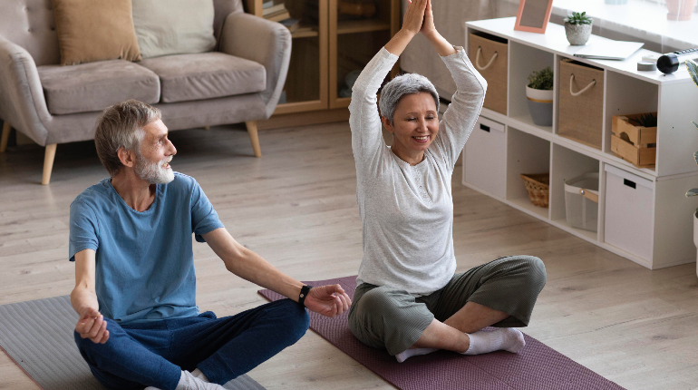 A senior resident performing balance exercises with a therapist at an osteoporosis elder care home in India