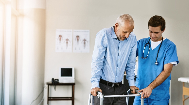 A senior resident performing supervised physiotherapy after surgery at a residential facility for elders with 24x7 healthcare support