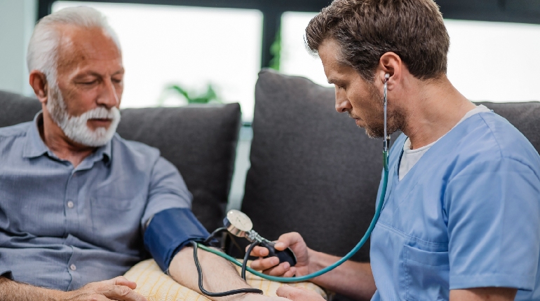 A specialized nurse performing a glucose check for a resident at a senior care facility with round the clock healthcare in India