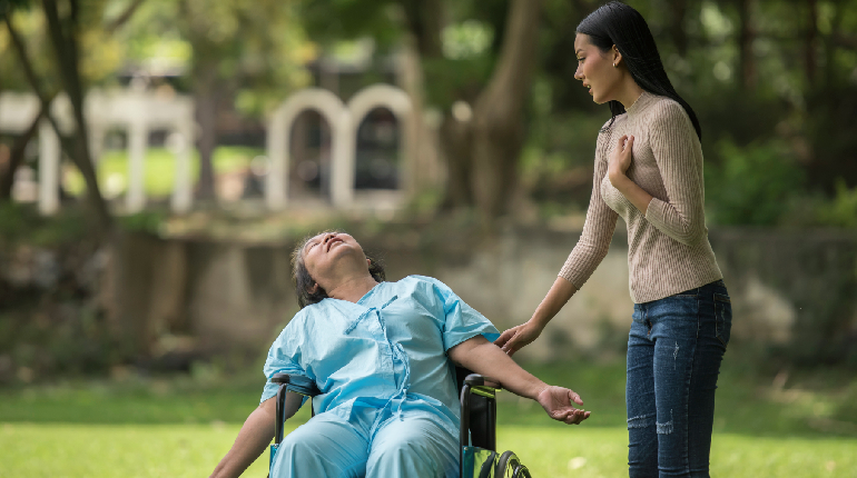 A staff member providing on-site assistance for elderly residents in a wheelchair-accessible garden